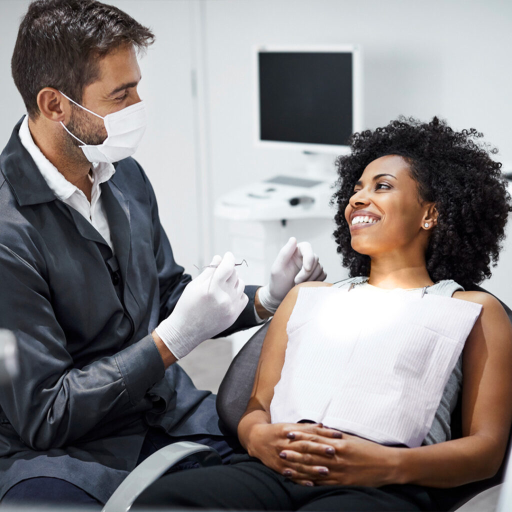 dentist holding a periodontal probe about to check a female patient's teeth